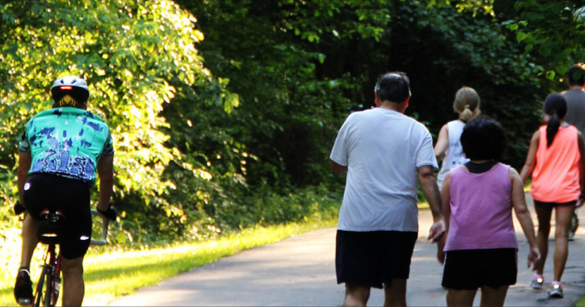 Person on bike and people walking outside on a trail