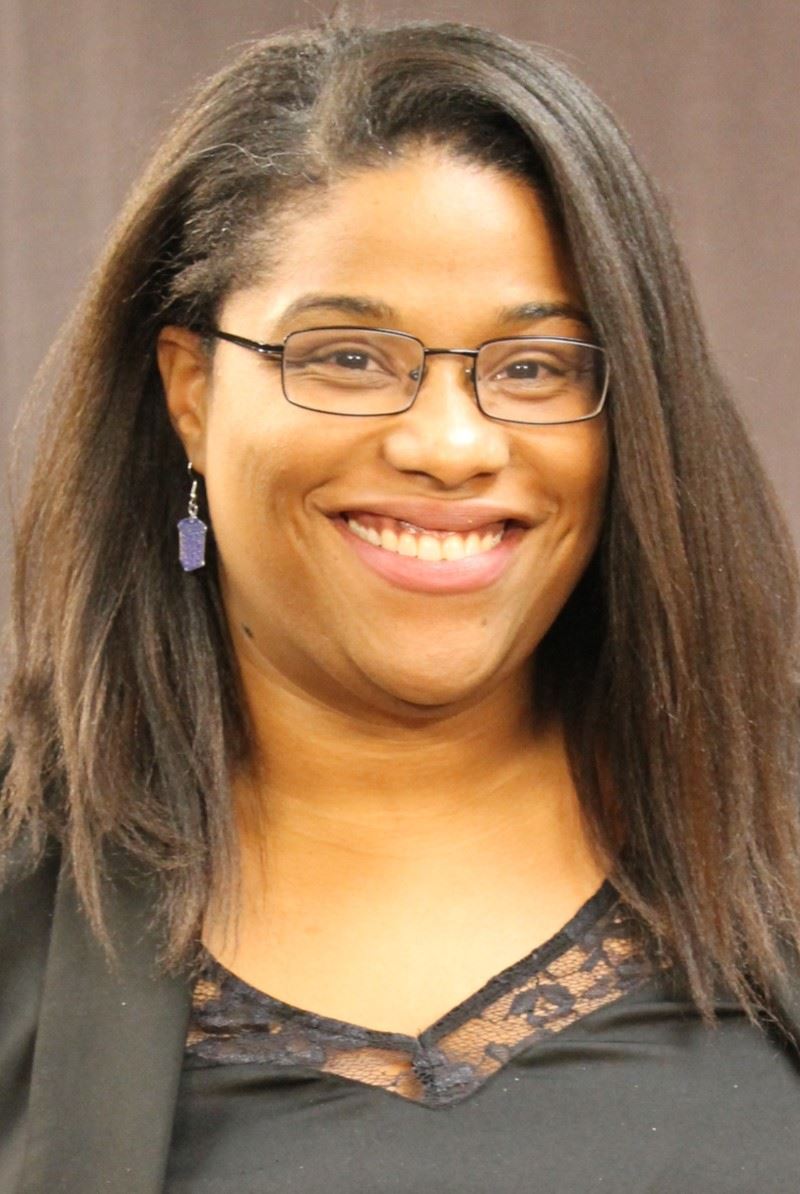 Headshot of woman smiling with glasses and brown hair 