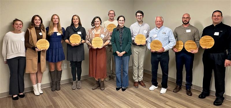 A group of people posing for a photo with awards.