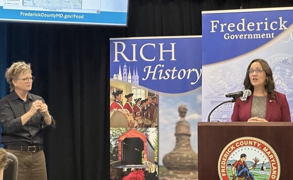 A woman standing at podium speaking at a press conference. 